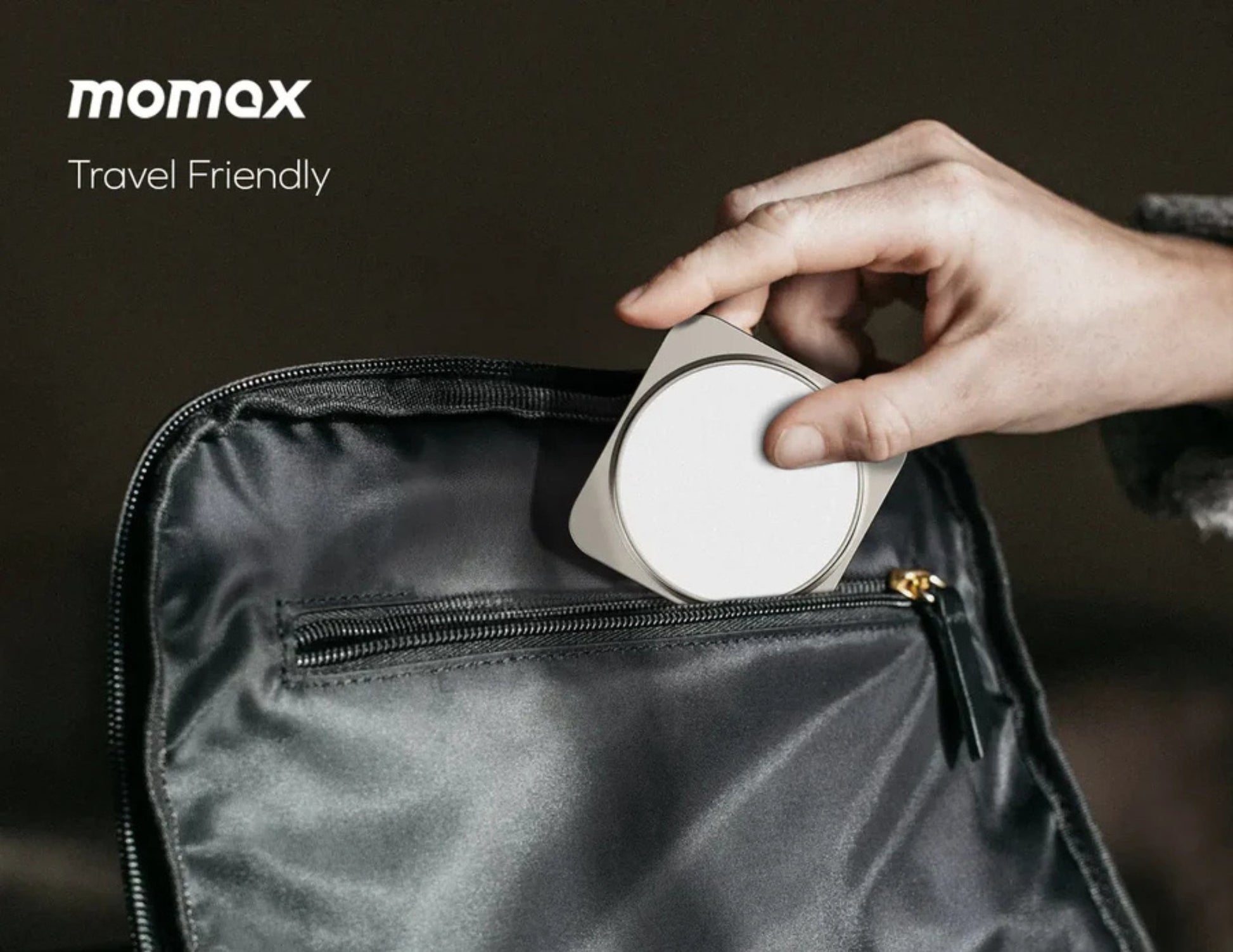 Person placing a white circular device into a black bag with 'momax' branding.