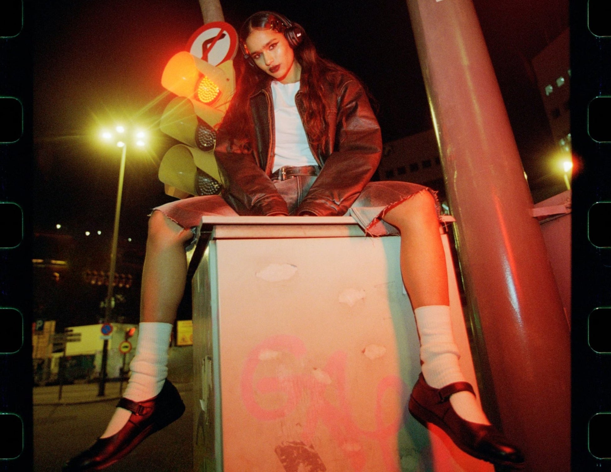 Person sitting on a box with neon lights and street signs in the background