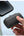 Hand holding a Baseus Compact Fast Charging Power Bank iP Edition with phone and person wearing green socks in the background