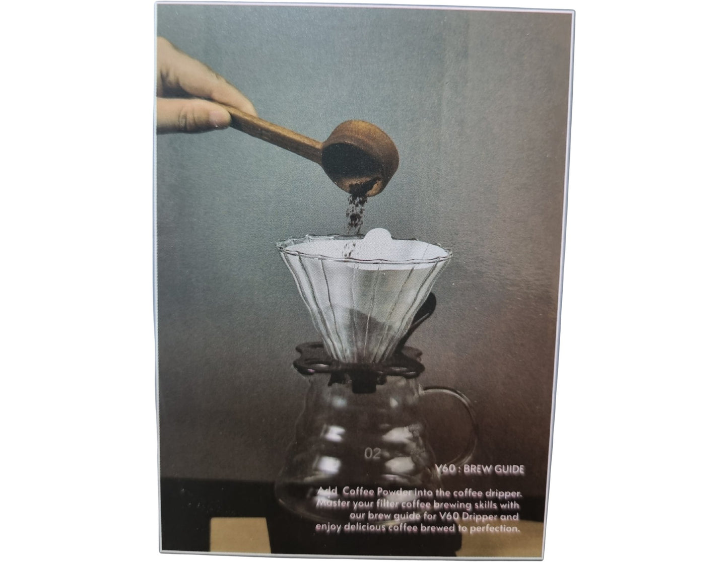 Coffee brewing process with a gloved hand using a coffee dropper over a glass carafe.