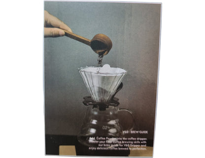 Coffee brewing process with a gloved hand using a coffee dropper over a glass carafe.