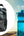 Black pouch and blue water bottle with a person exercising outdoors.