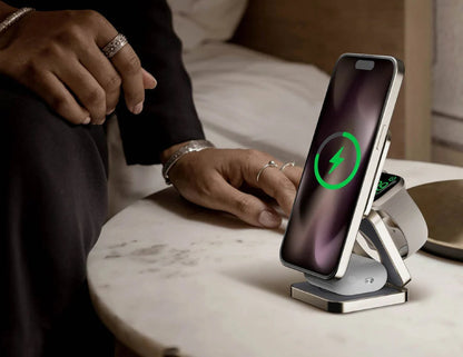 Person using a wireless charging stand with two devices on a marble surface.