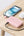 Pink Belkin BoostCharge BPB021hq 10K 20W power bank with USB-C cable from Thabthaba Store with white earbuds, and smartwatch on a wooden table.