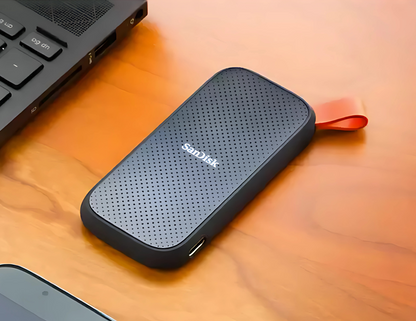 SanDisk Portable SSD 1TB SDSSDE30-1T00-G26 on a desk beside a laptop.